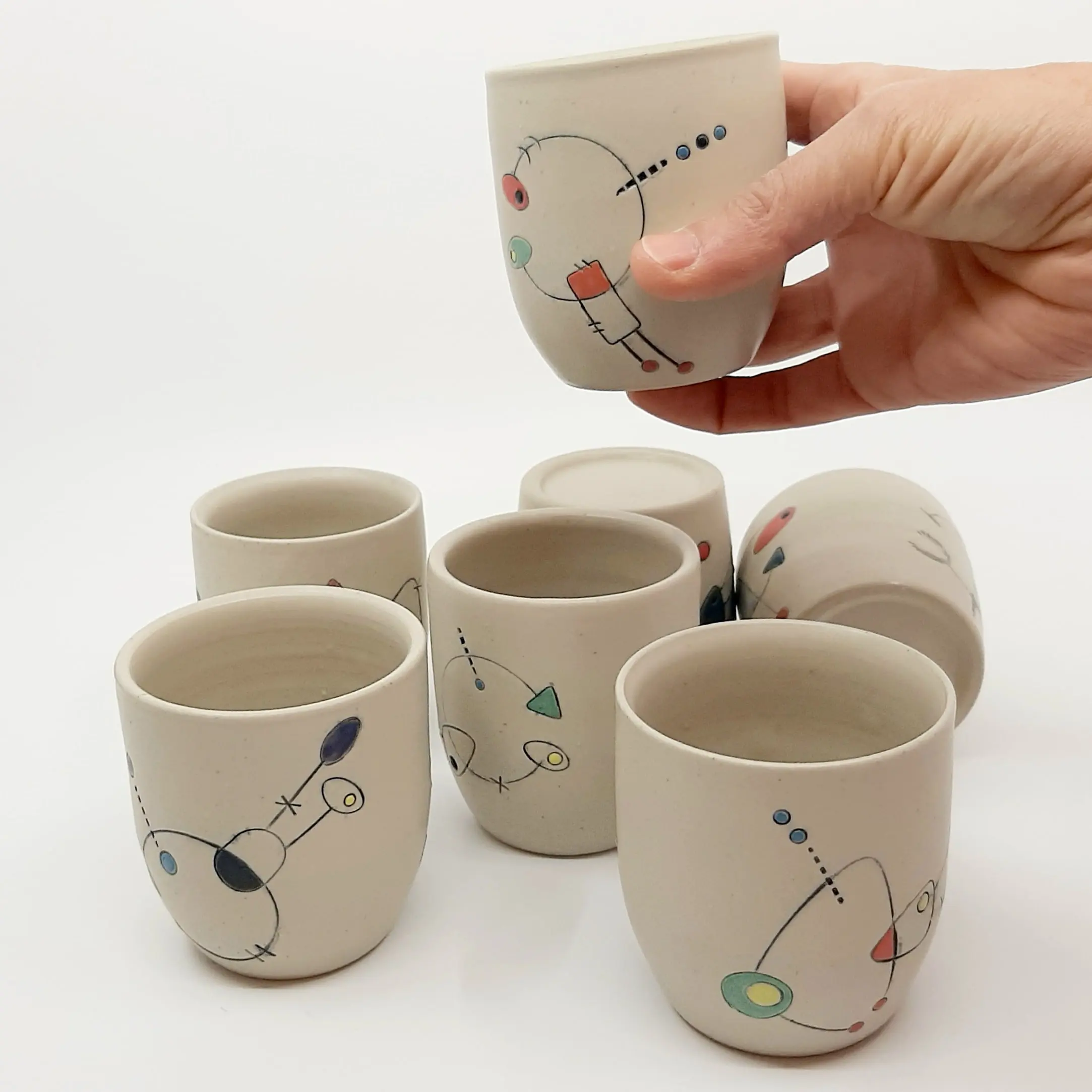 main qui tiens une tasse au dessus de six autres tasses-collection Geometrik