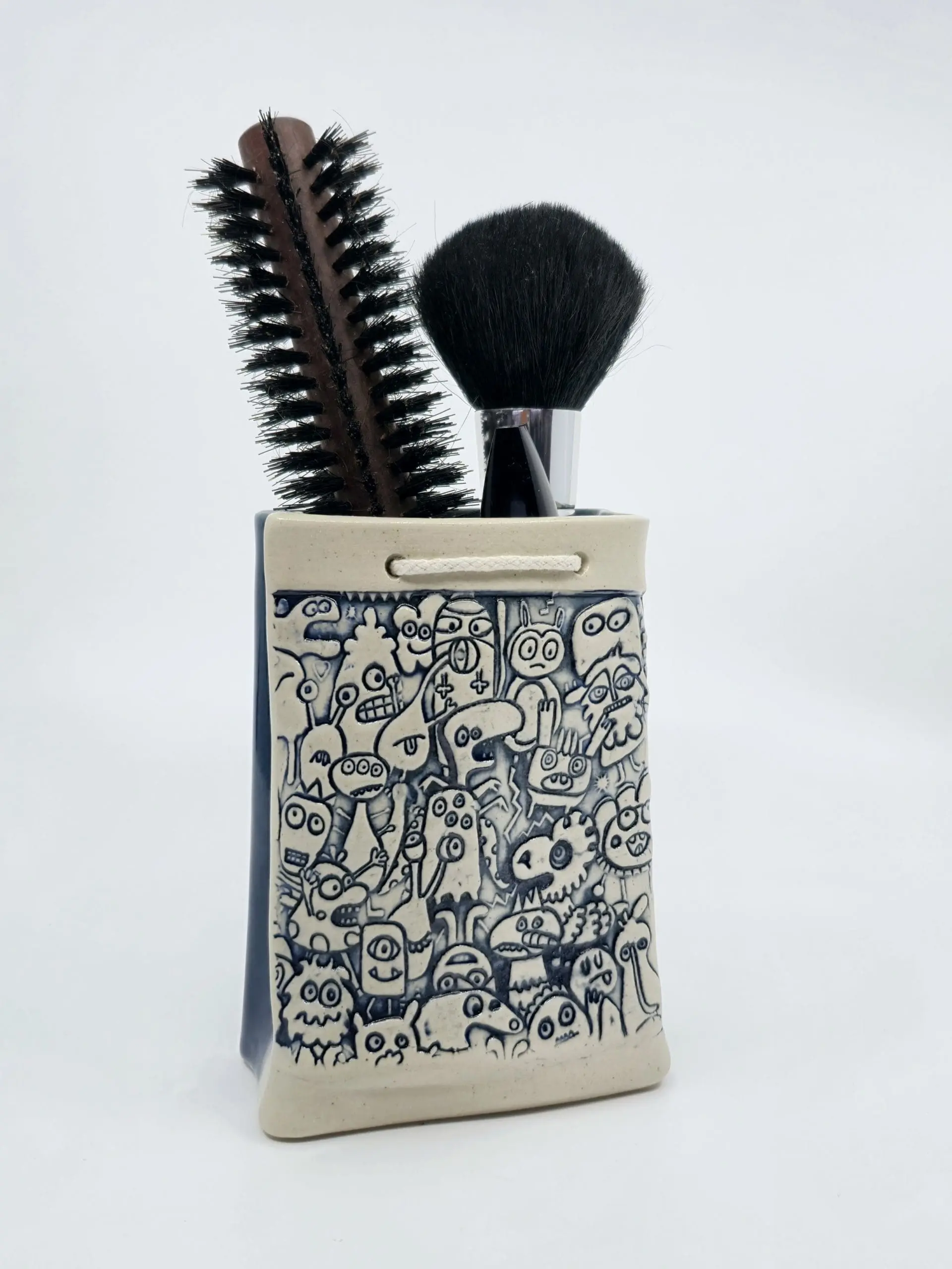 un pot engobé avec une brosse et un pinceau dedans